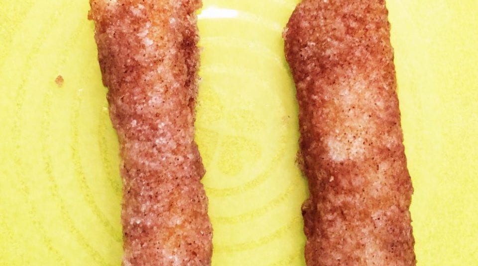 Two cinnamon sugar churros on a yellow plate.