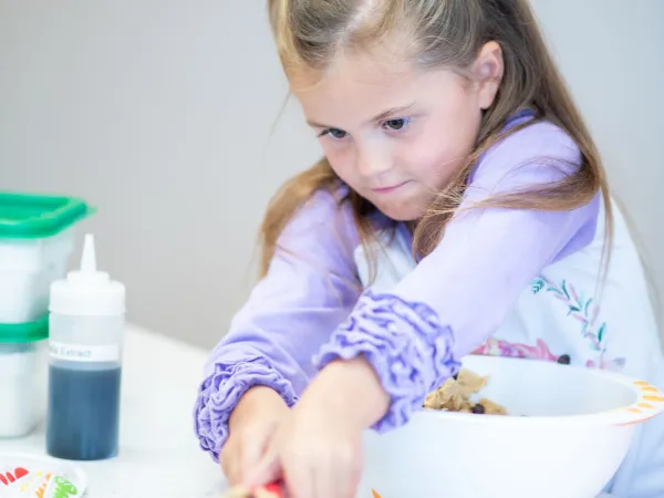 Girl with pigtails placing cookie dough on a baking sheet.