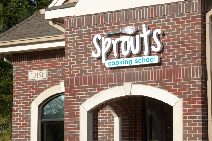 Brick building with 'Sprouts Cooking School' sign above arched window.