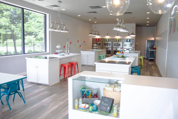 Modern cooking classroom with islands, stools, ovens, and a window view.