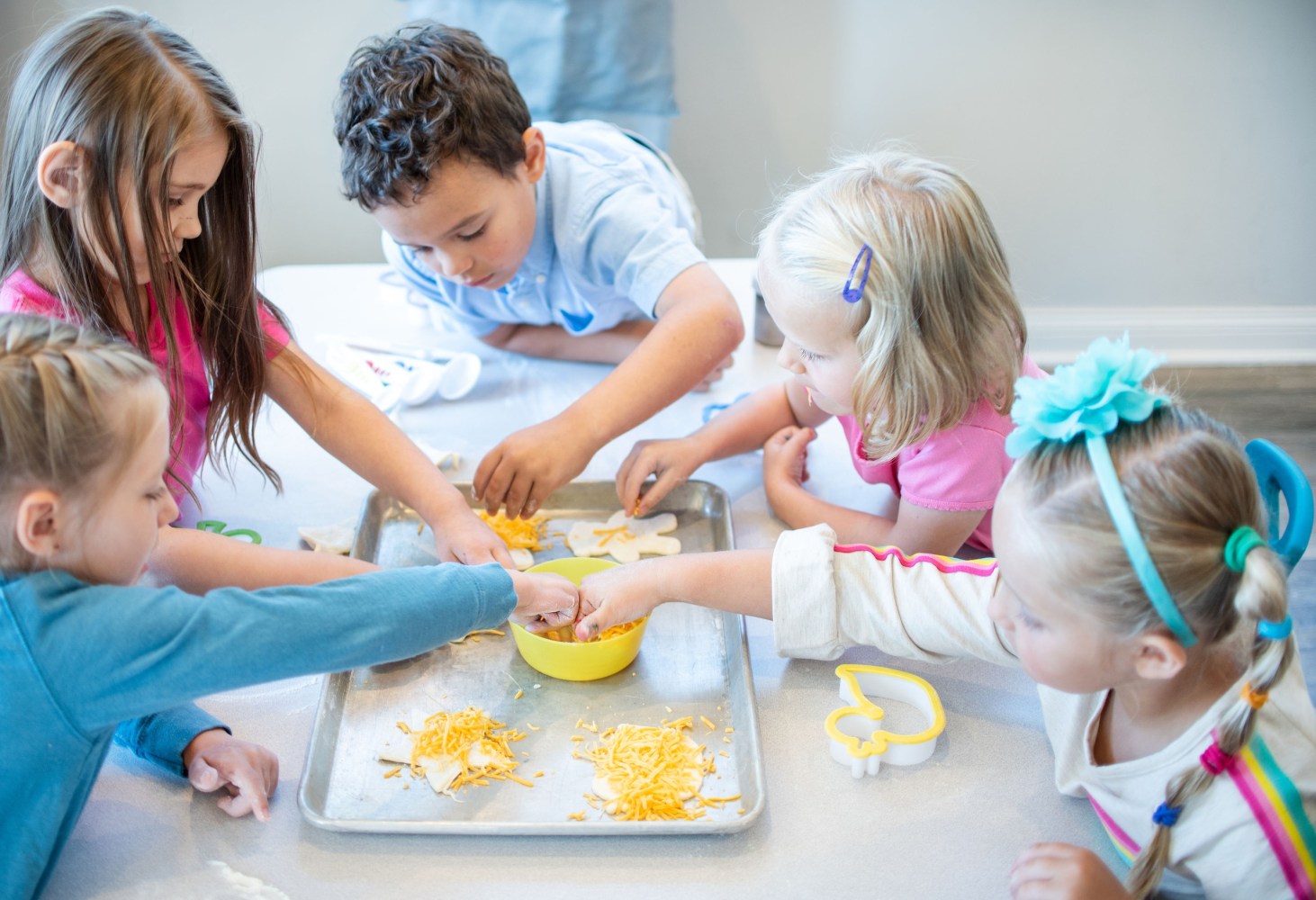 Children gathered around a table, making crafts with shredded materials and molds.