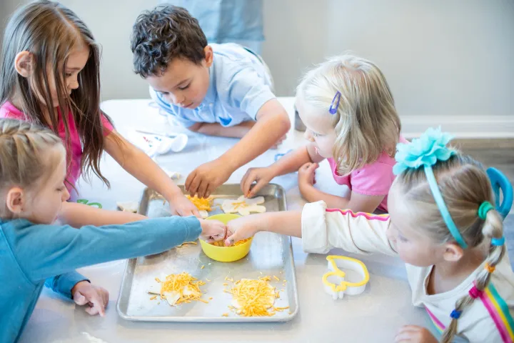 Children gathered around a table, making crafts with shredded materials and molds.