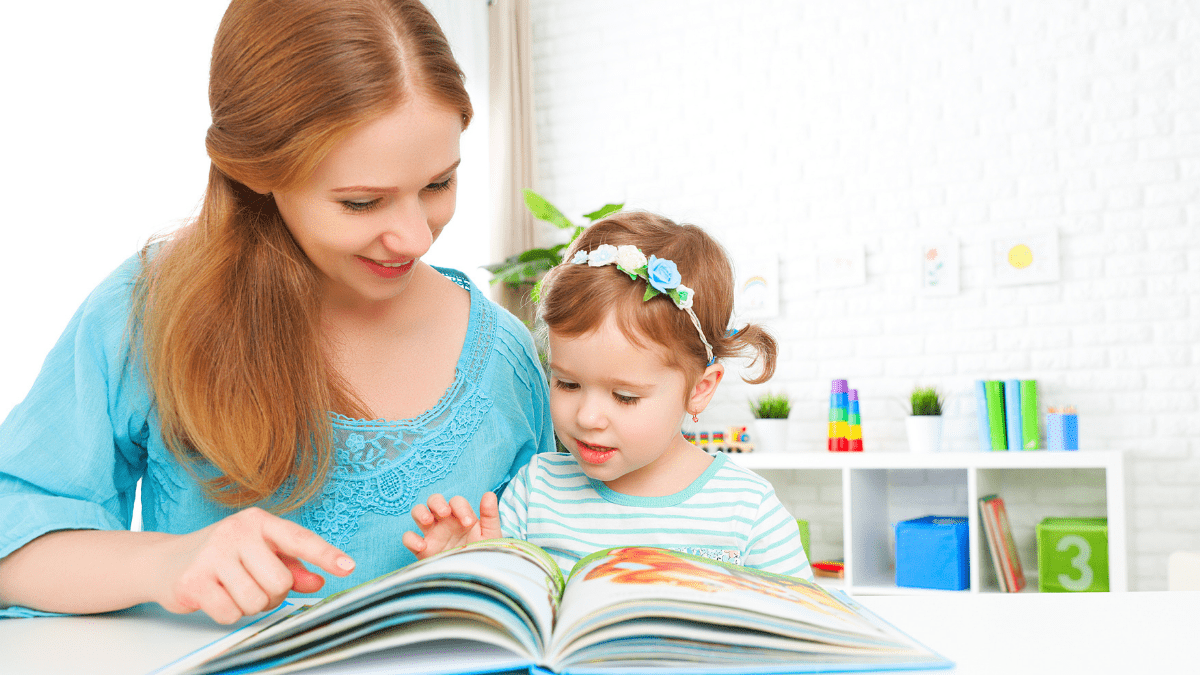 Woman and child reading a book together at a table.