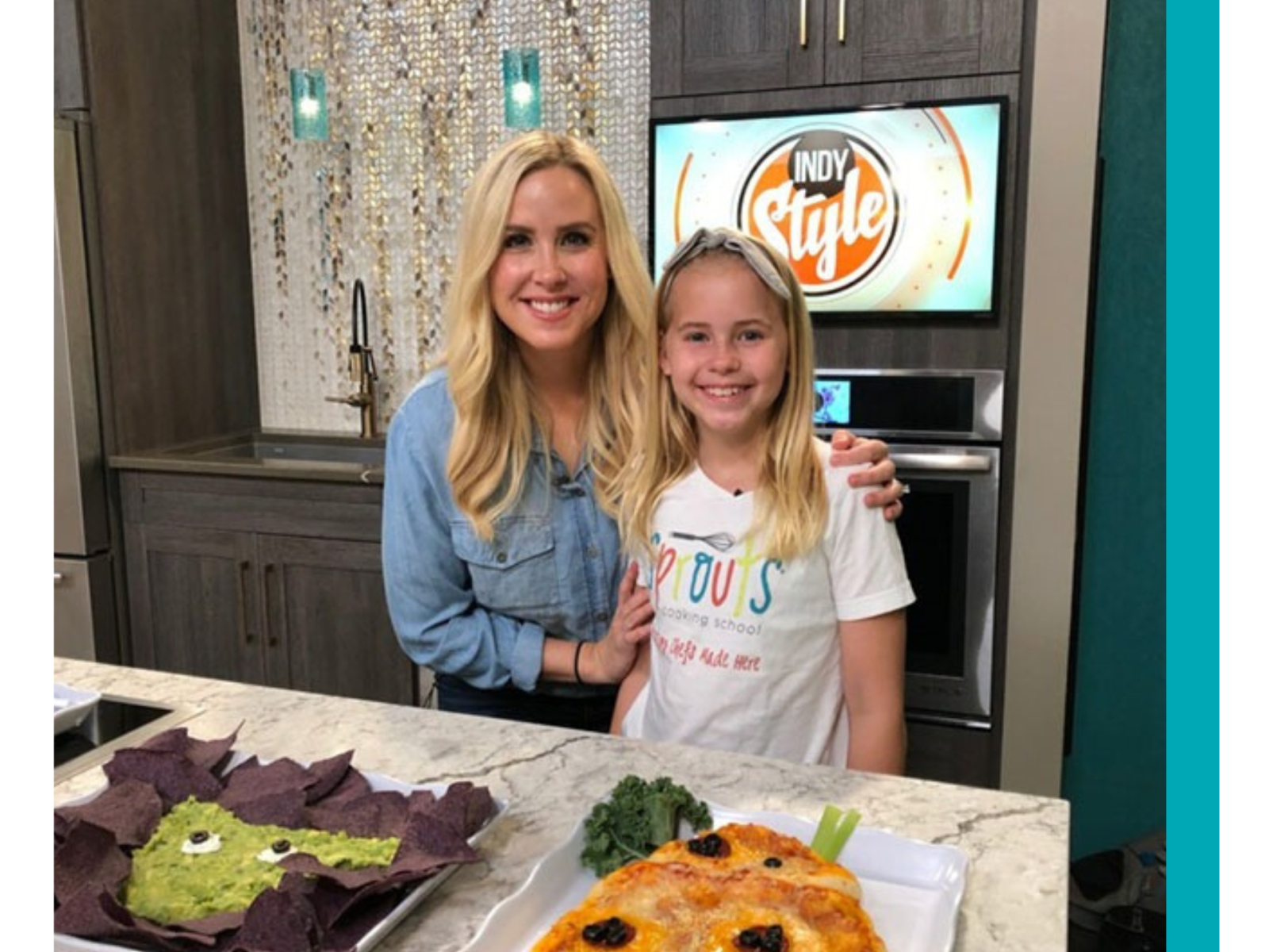 Two people in a kitchen setting with food displayed on the counter.