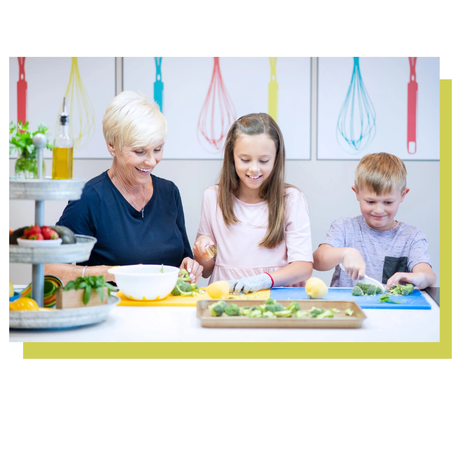 Woman and two children cutting vegetables in a kitchen.