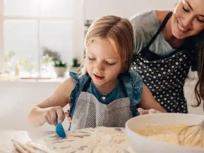 Mother and daughter baking together, with flour and a mixing bowl on the kitchen counter.