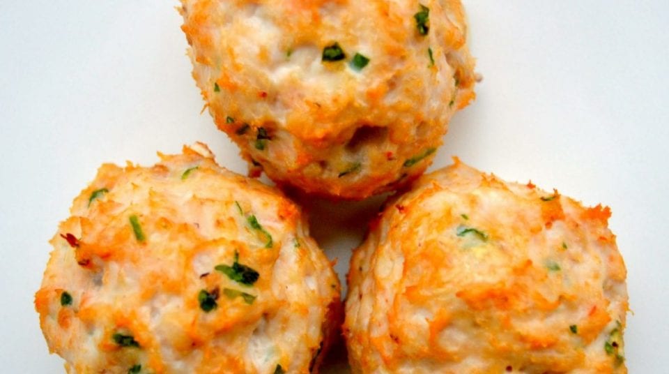 Three baked chicken balls with herbs on a white background.