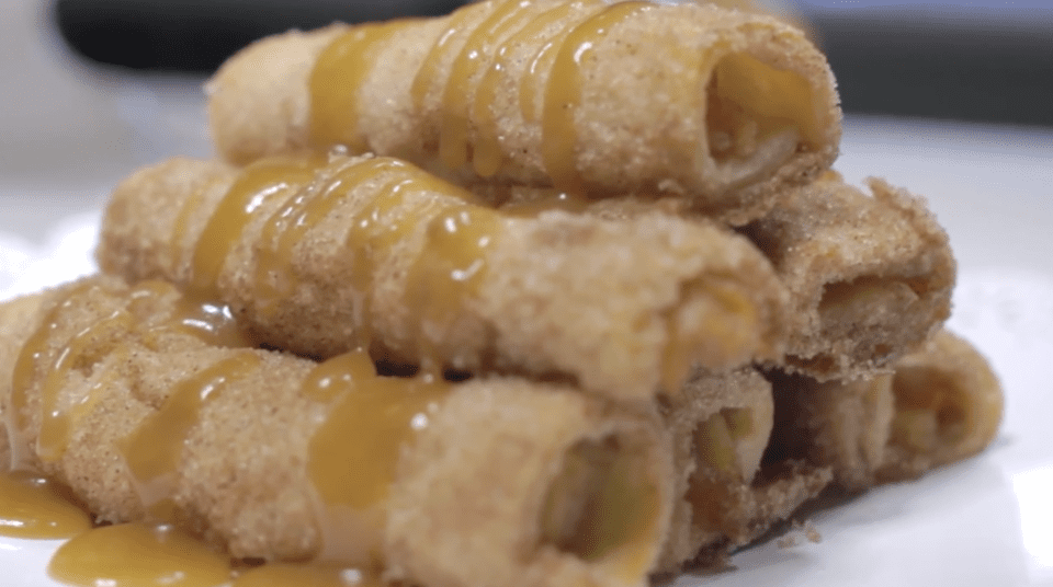 Stack of rolled pastries drizzled with caramel sauce on a plate.