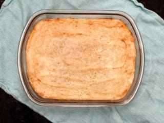 Baked casserole in a glass dish on a light blue cloth.